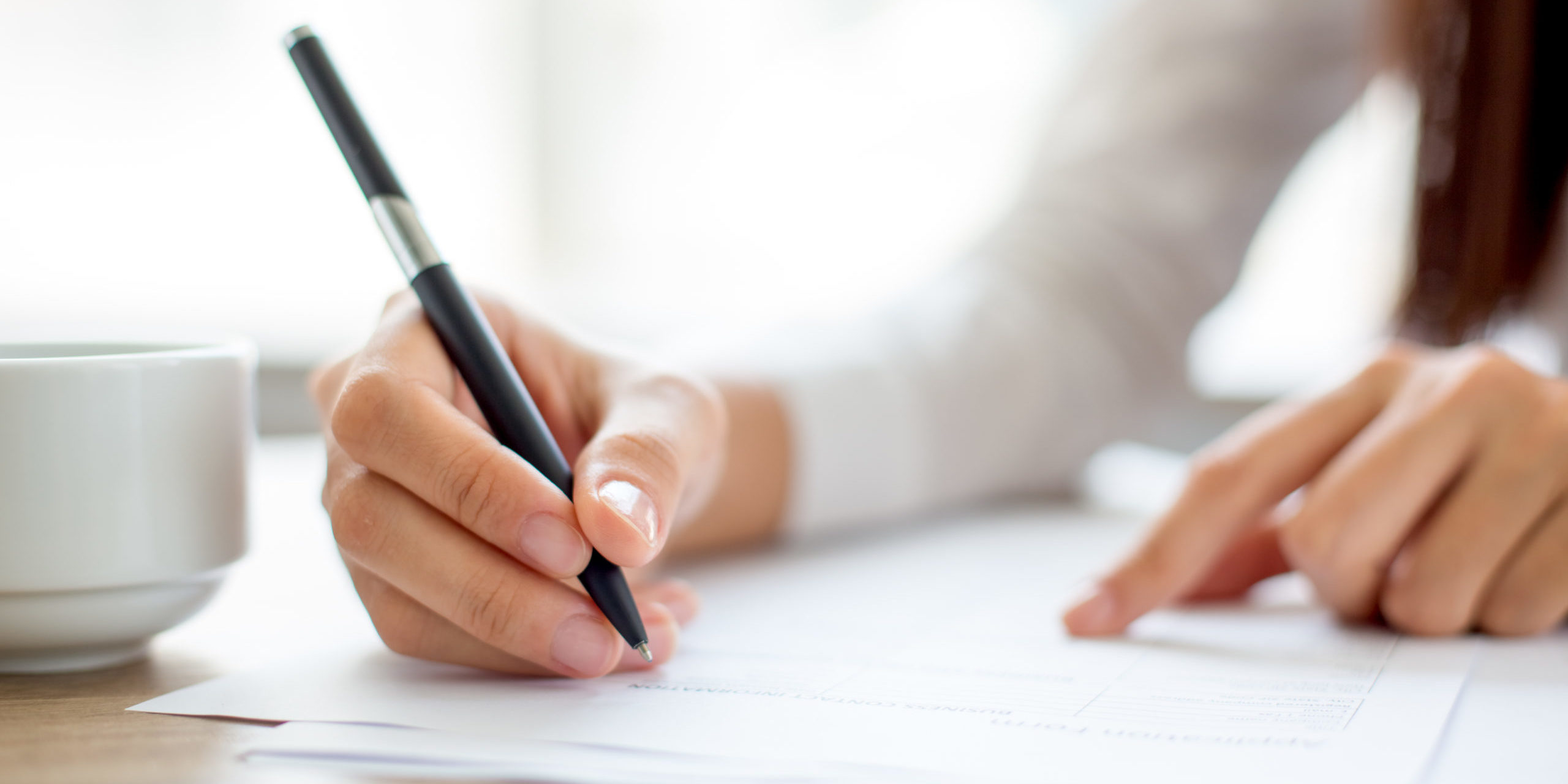 Hand of businesswoman writing on paper in office