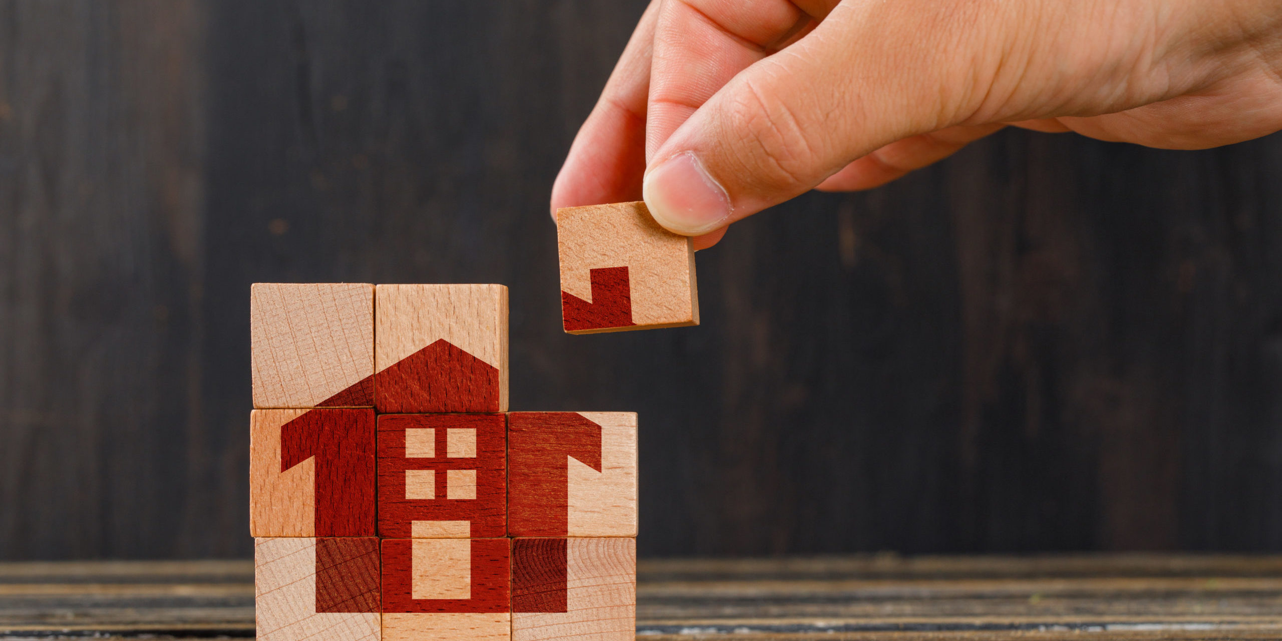 Stay at home concept on wooden background side view. hand holding wooden cube.